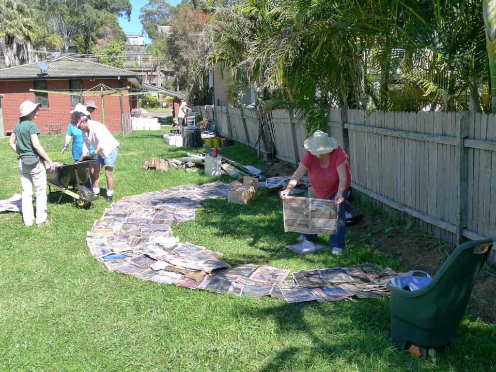 Members laying wet newspaper on the lawn